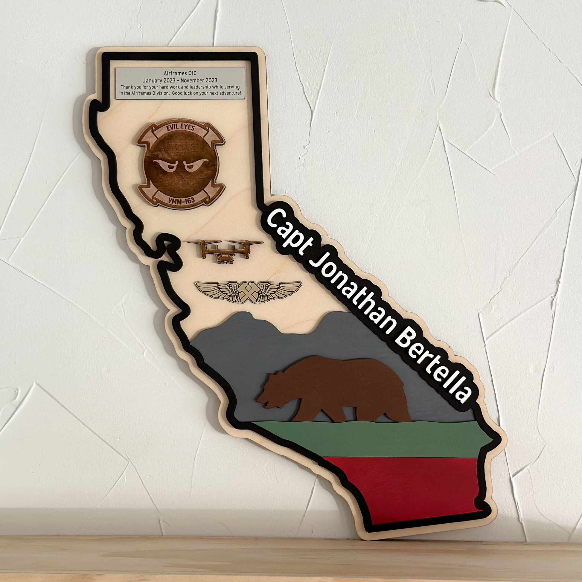 Engraved military name, rank, and service details on state-shaped wooden plaque